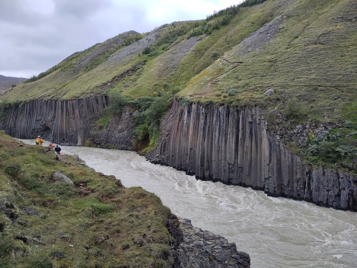 Der graue Gletscherfluss fließt durch die Schlucht Stuðlagil mit ihren Basaltsäulenwänden