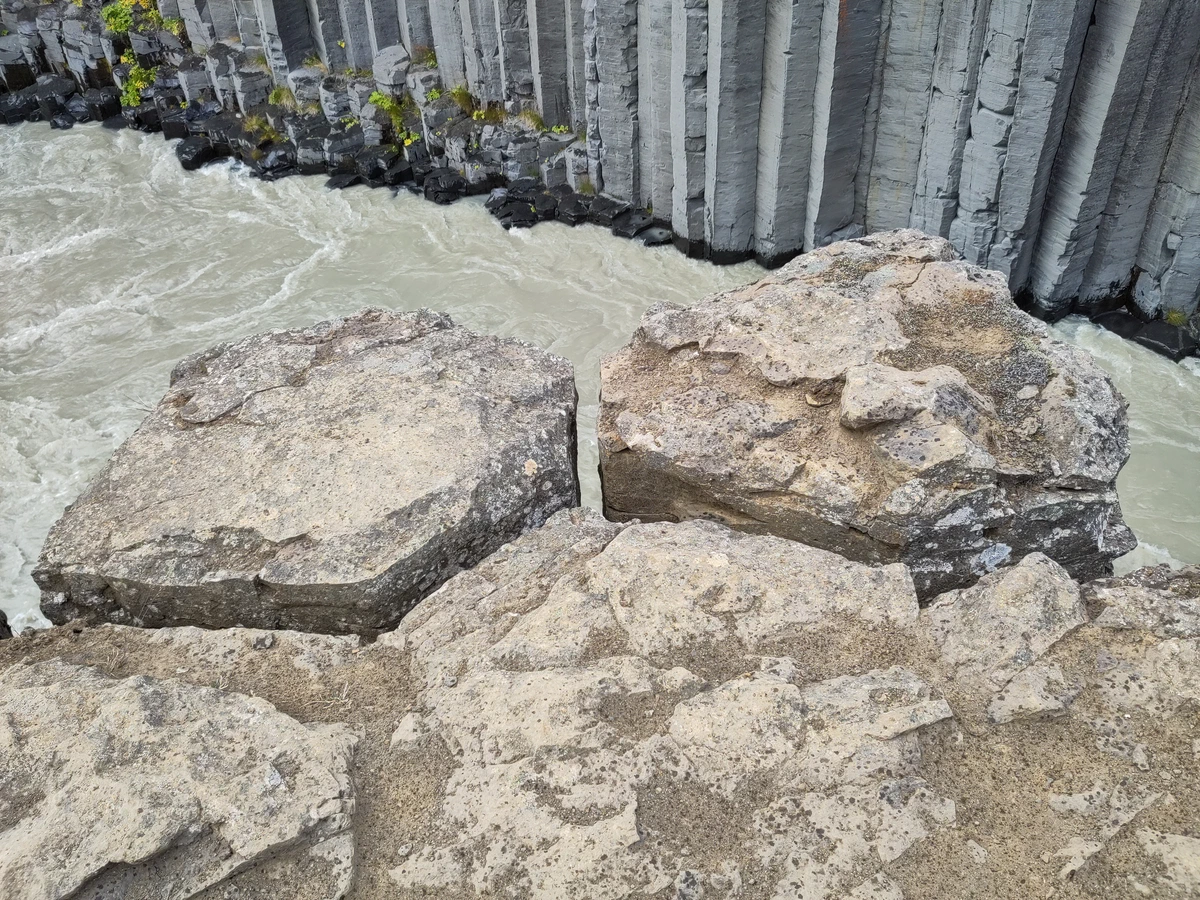 Große helle Felsblöcke über dem Fluss, gegenüber Basaltsäulen