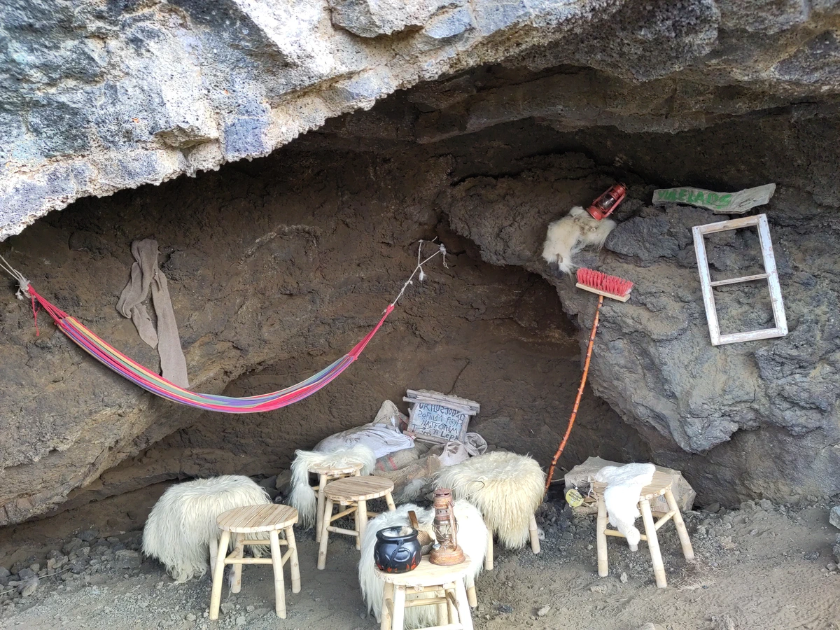 Höhle der Weihnachtsgesellen: Hängematte, Schemel mit Schaffellen und Hausrat unter einem Lavaüberhang