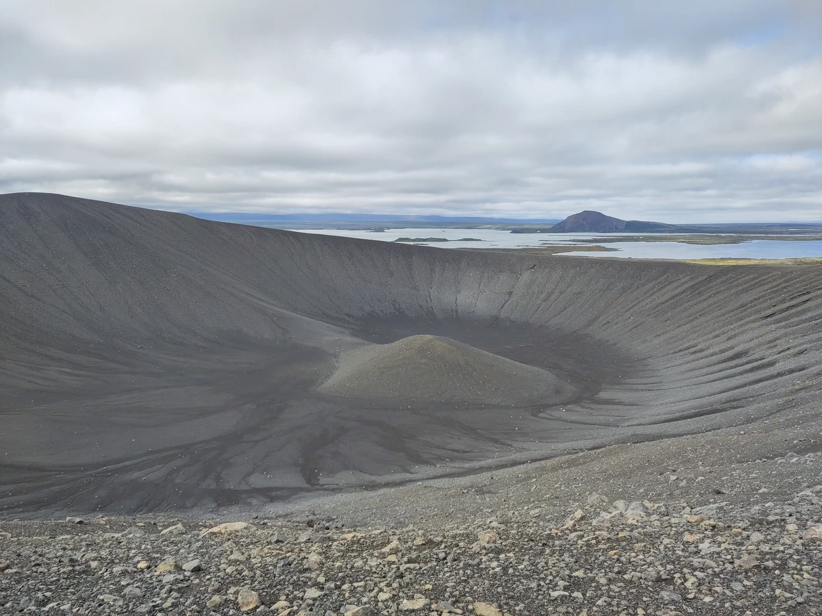 Blick in den weiten Krater des Hverfjall mit einem kleinen Hügel in der Mitte, dahinter der Mývatn
