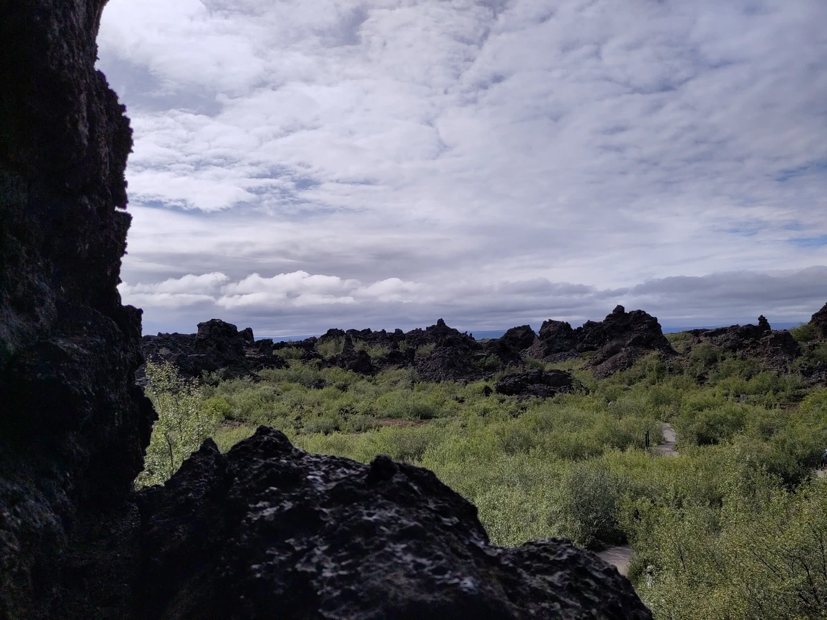 Blick aus dem Schatten einer Lavawand über das zerklüftete Lavafeld