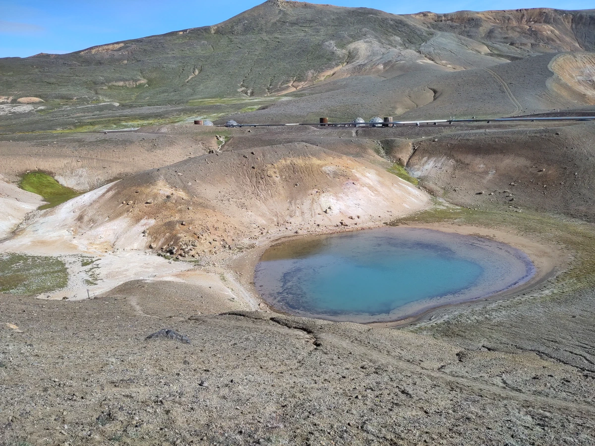 Kleiner türkisblauer Kratersee zwischen hellen, schwefelgelben Hängen