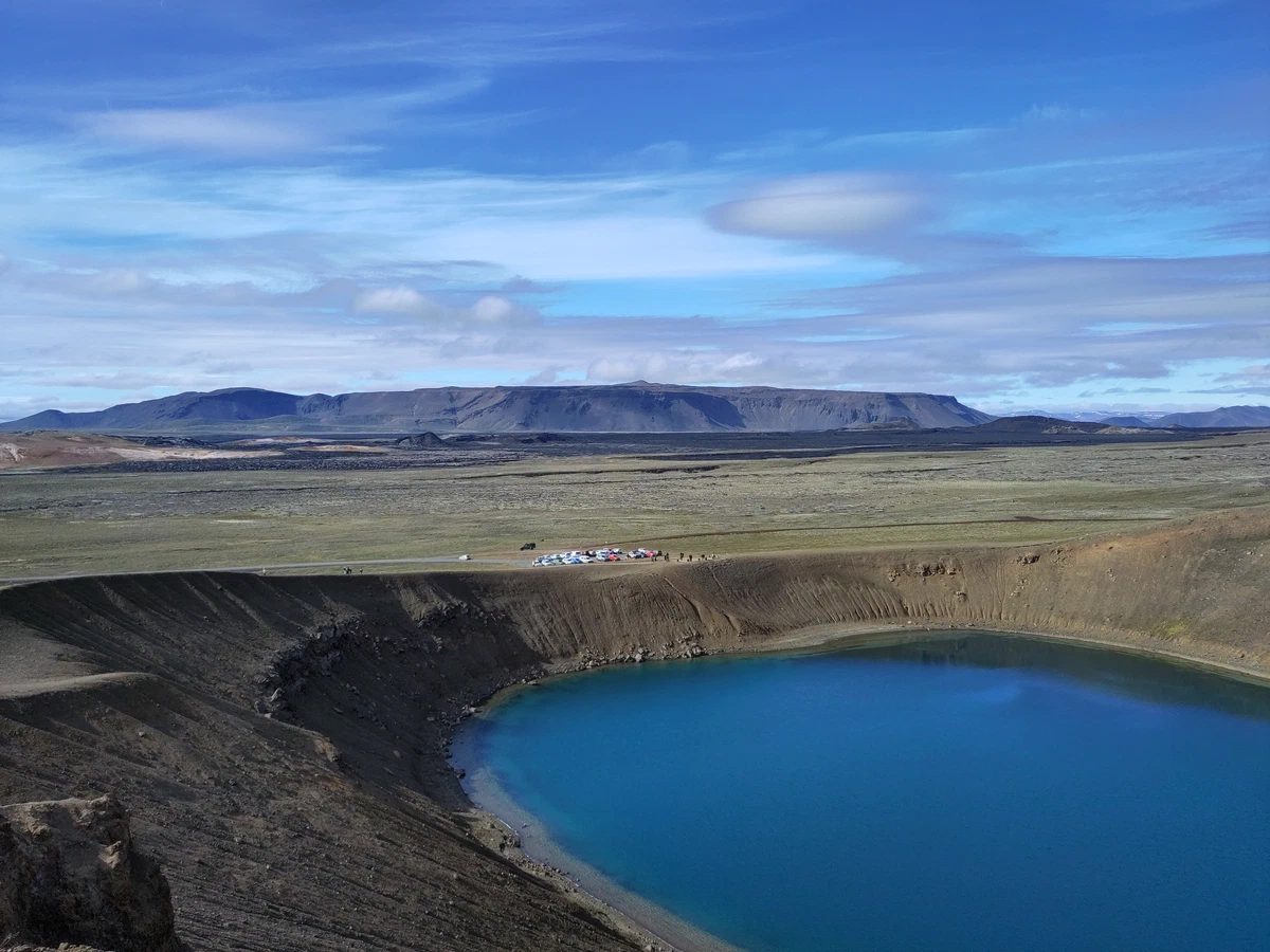 Tiefblauer Kratersee Víti von oben, dahinter ein Tafelberg