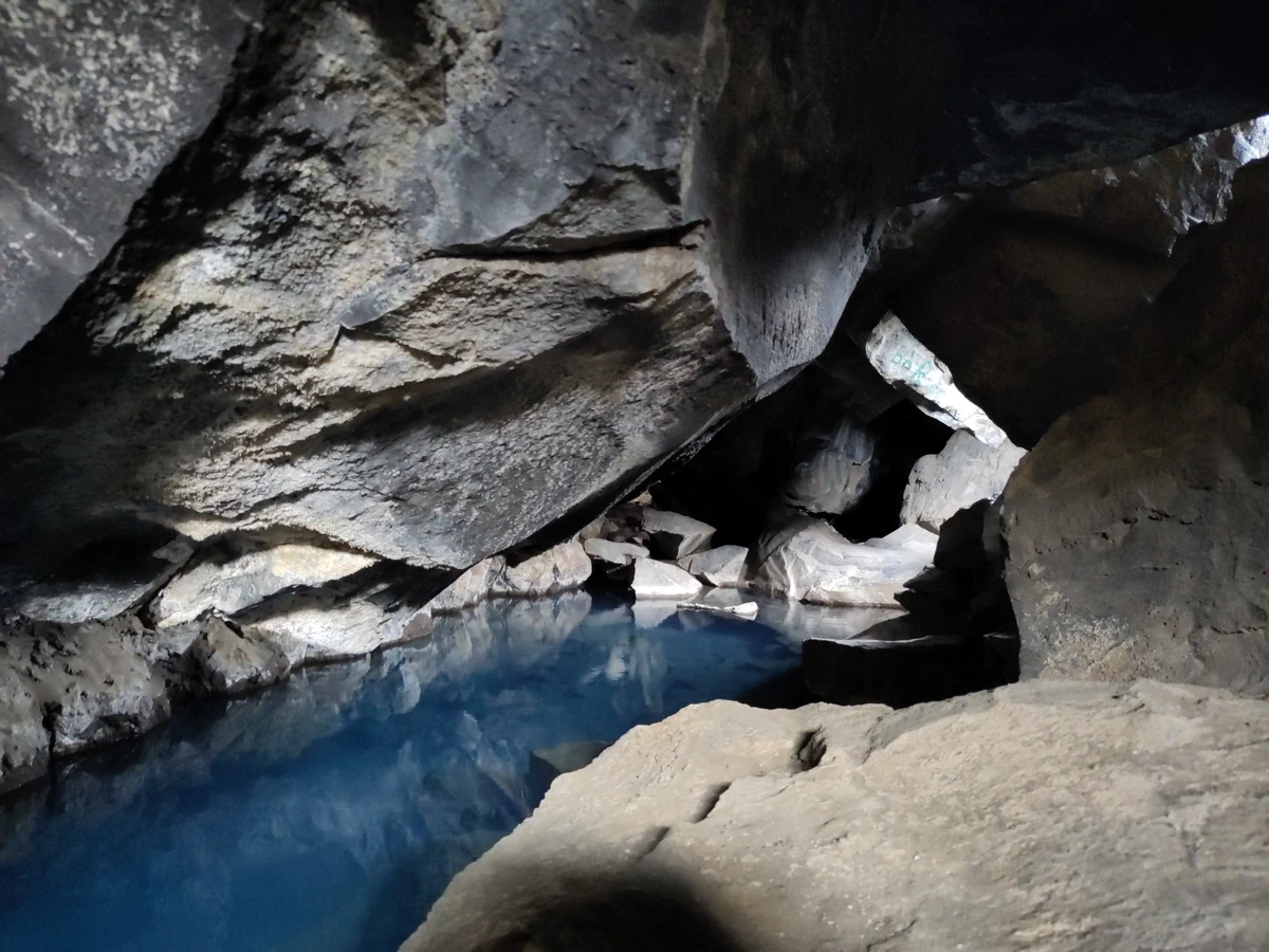Blaues Wasser in der Grotte Grjótagjá unter wuchtigen Felsblöcken