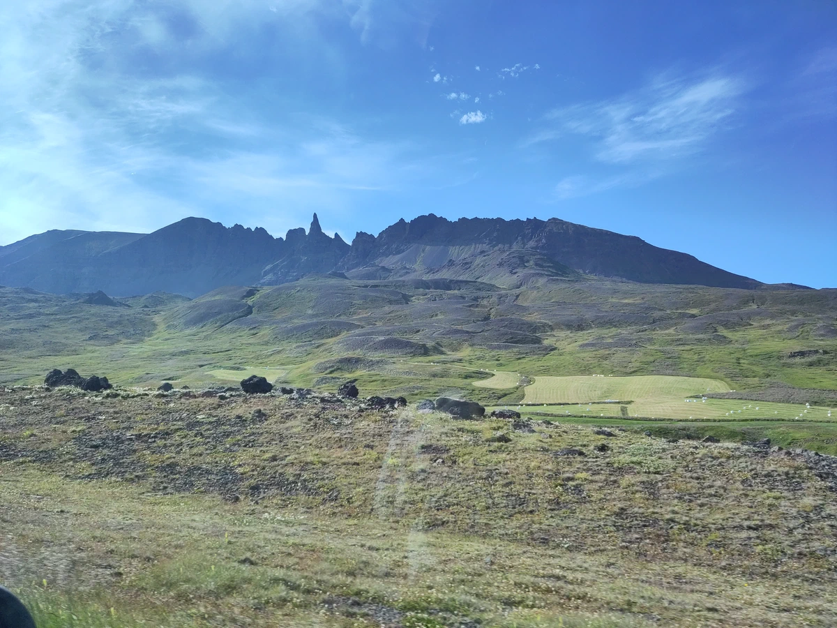 Gezackter Bergkamm über grünen Hängen unter blauem Himmel