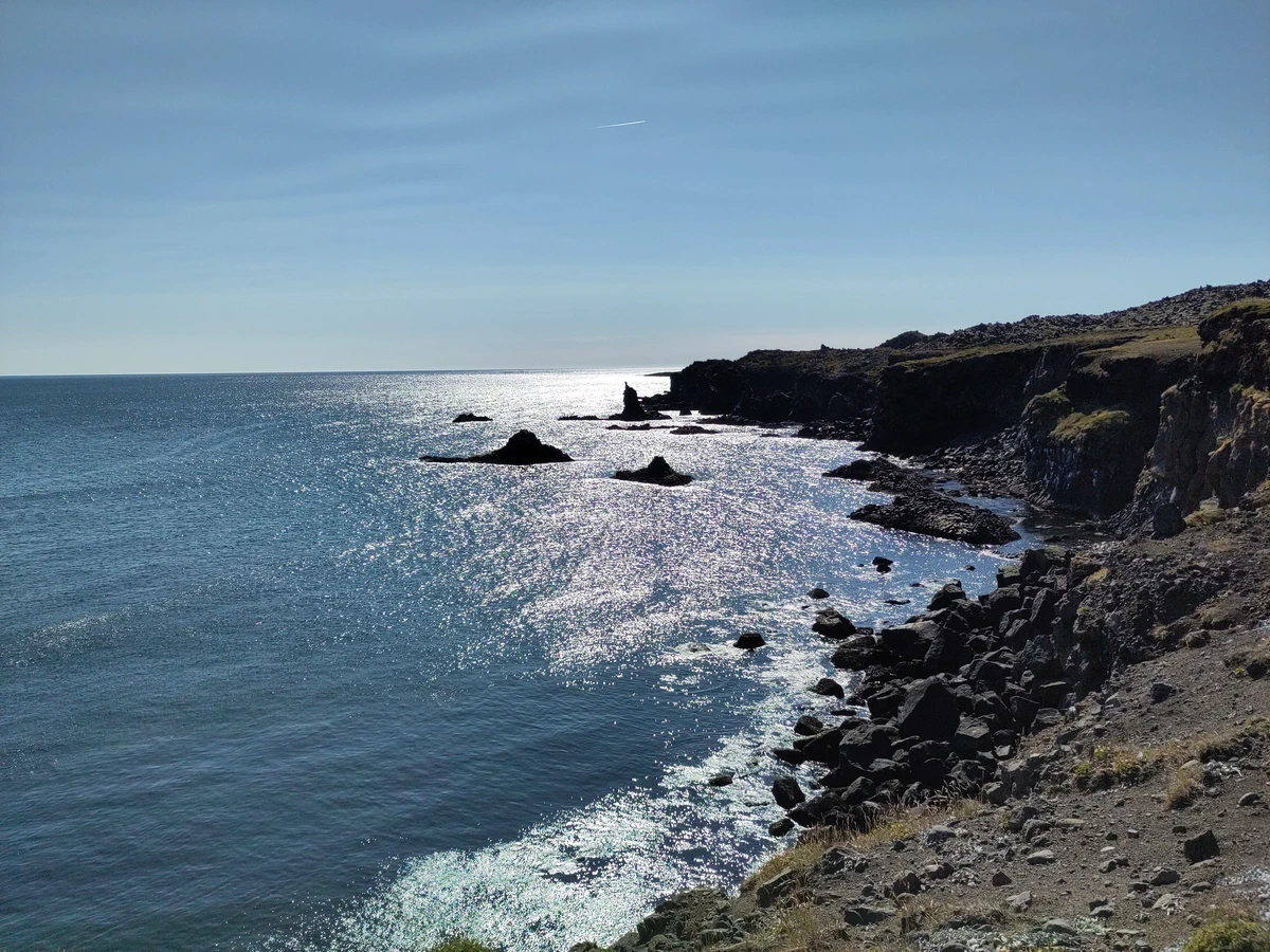 Felsküste im Gegenlicht, das Meer glitzert in der Sonne