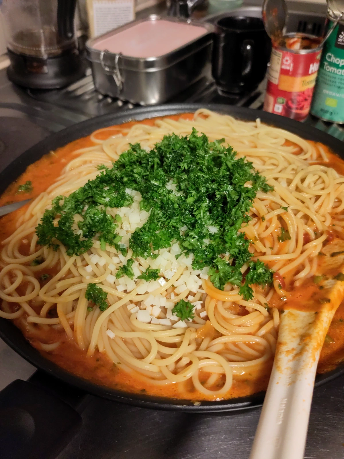 Spaghetti in Tomatensauce mit gehackter Petersilie und Zwiebeln in der Pfanne