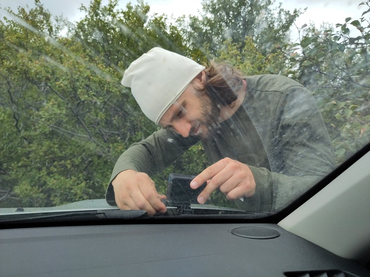 Ein Mann mit Mütze befestigt von außen die Kamera an der Windschutzscheibe