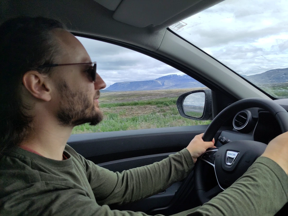Der Fahrer mit Sonnenbrille am Lenkrad, durch das Fenster weite Landschaft