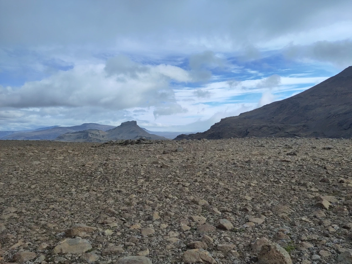 Endlose Geröllebene mit dunklen Bergen unter Wolken
