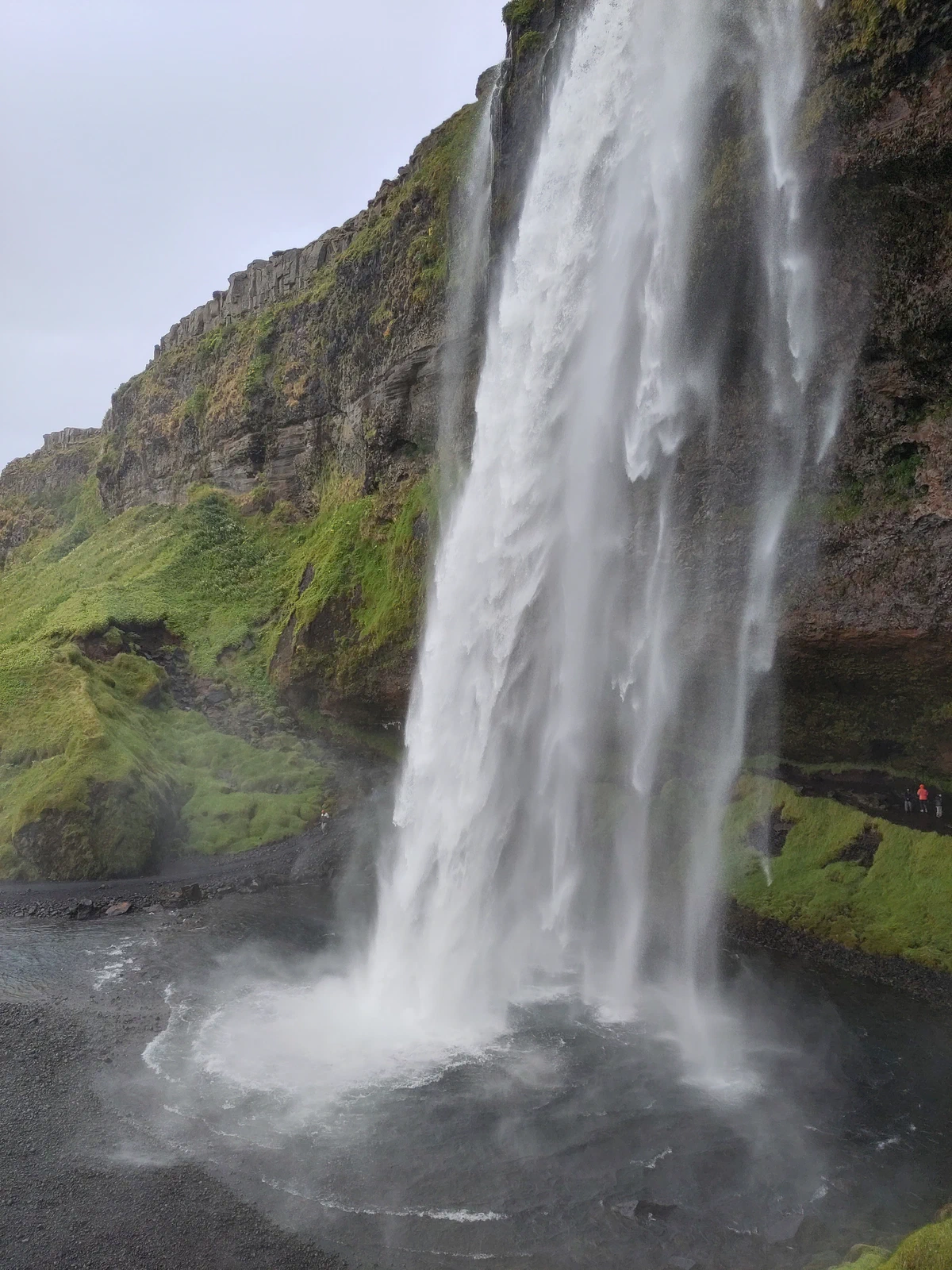 Seljalandsfoss stürzt von einer überhängenden Felswand in ein Becken