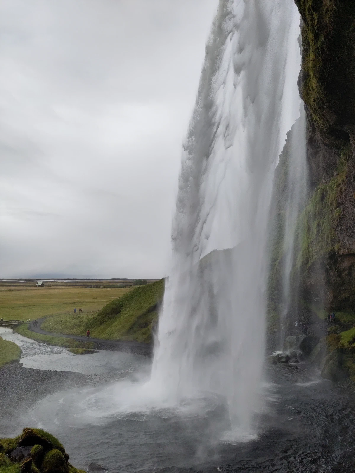 Blick von der Seite hinter den Wasservorhang des Seljalandsfoss