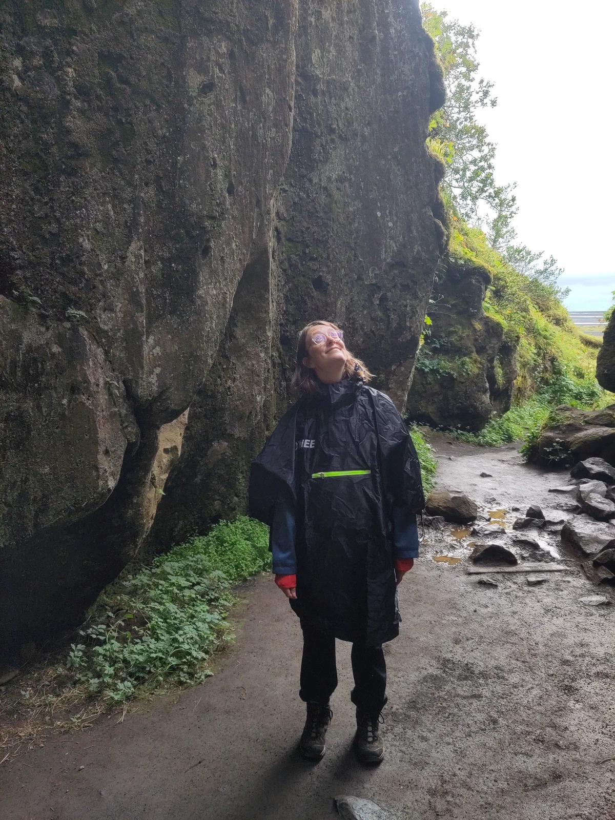 Eine Person im Regenmantel steht in einer engen Felsschlucht und schaut nach oben