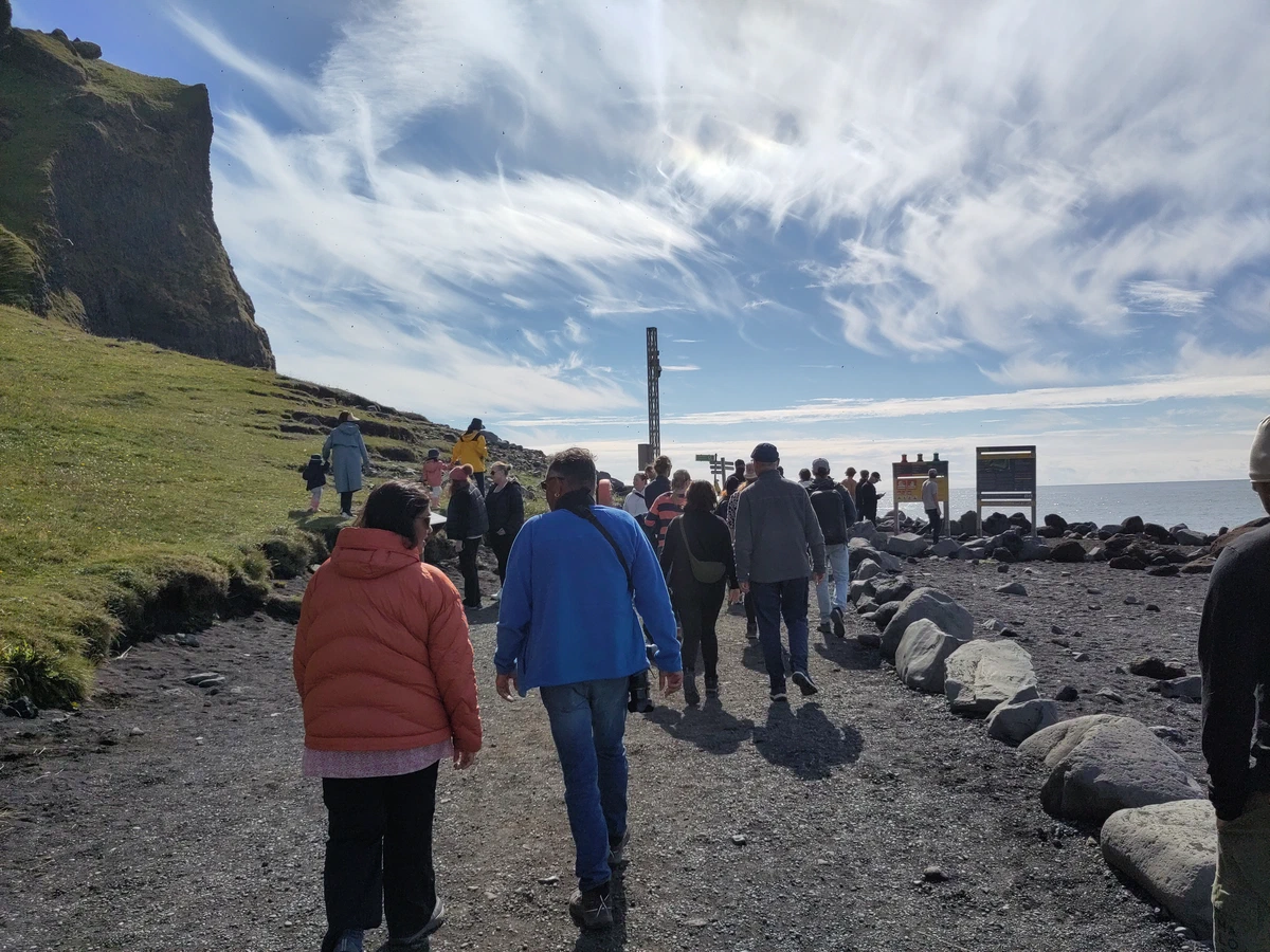Viele Besucher gehen auf dem Weg zum Strand Reynisfjara