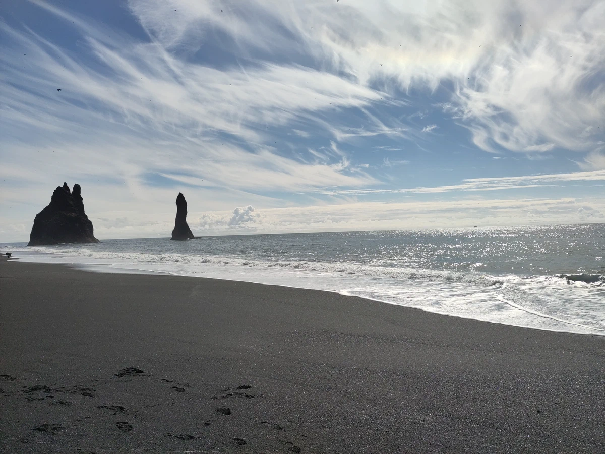 Schwarzer Sandstrand Reynisfjara mit den Felsnadeln Reynisdrangar im Gegenlicht