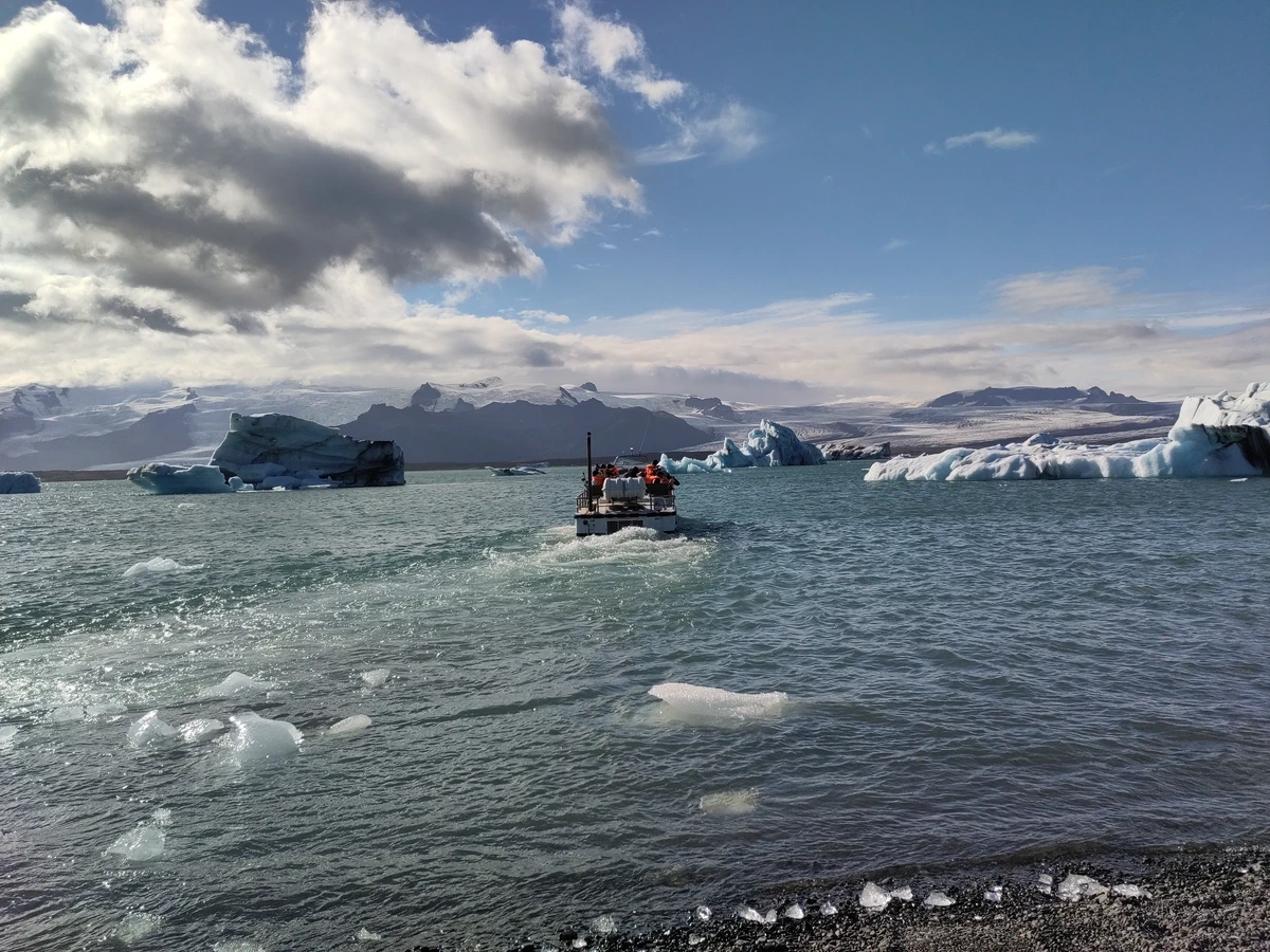 Ein Schlauchboot mit Besuchern fährt zwischen den Eisbergen über die Lagune