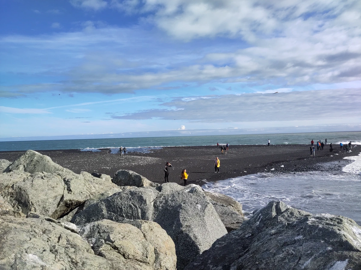 Schwarzer Strand Diamond Beach mit Besuchern, vorne große helle Felsblöcke