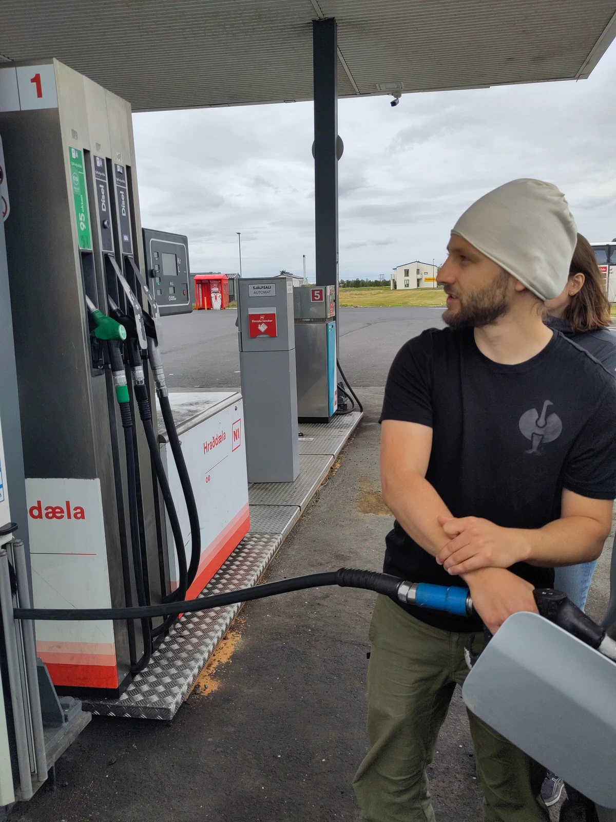 Ein Mann mit Mütze betankt das Auto an der Zapfsäule