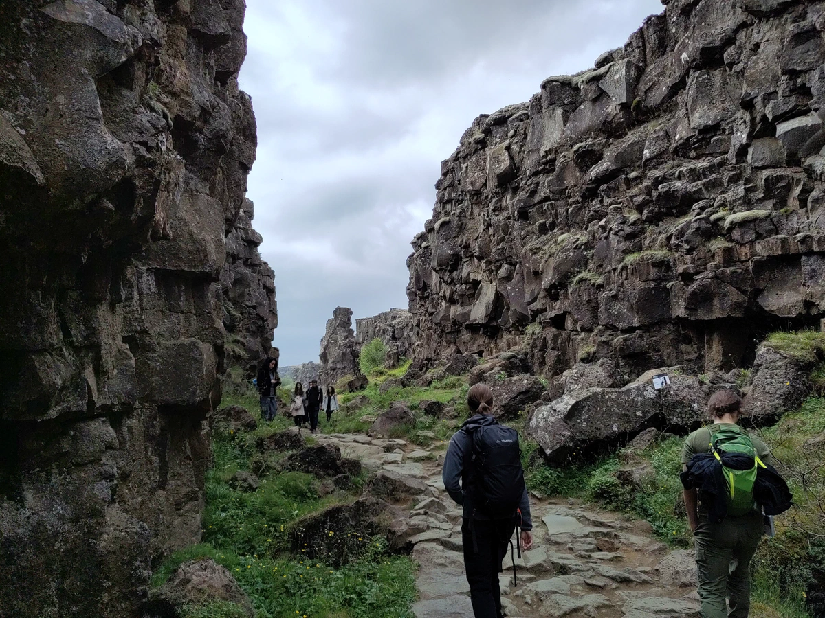 Wanderer mit Rucksäcken gehen auf einem Weg durch die Schlucht zwischen hohen Felswänden