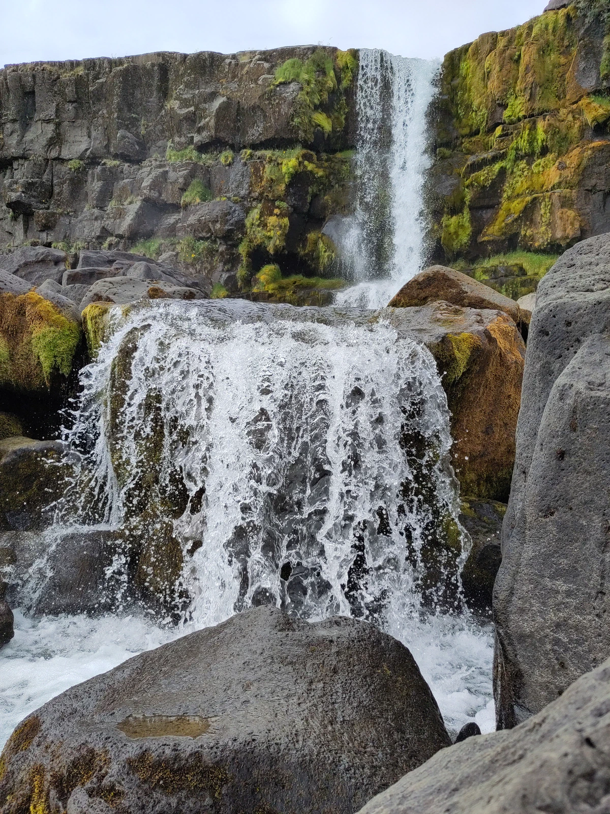Wasserfall in Þingvellir stürzt über eine Basaltwand zwischen große Felsbrocken