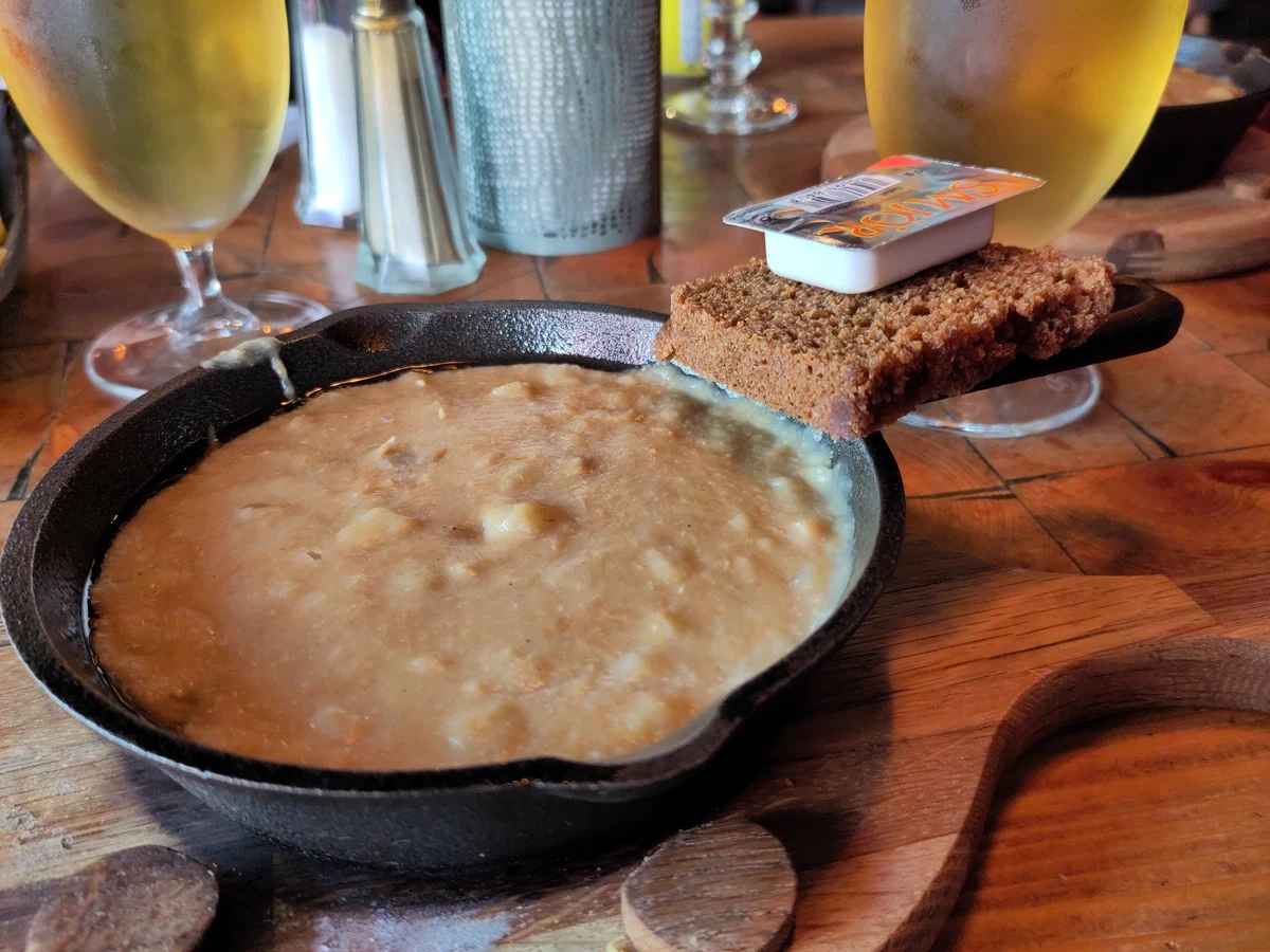 Plokkari, ein cremiges Fischgericht, in einer gusseisernen Pfanne mit dunklem Brot und Butter