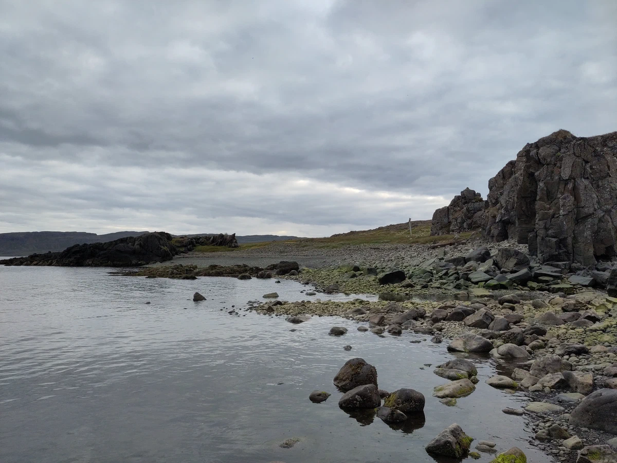 Steinige Küste mit dunklen Basaltfelsen am ruhigen Wasser