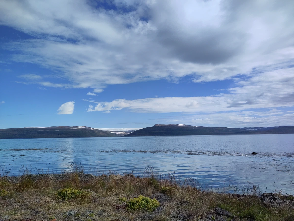 Ruhiger Fjord mit schneebedeckten Bergen am anderen Ufer