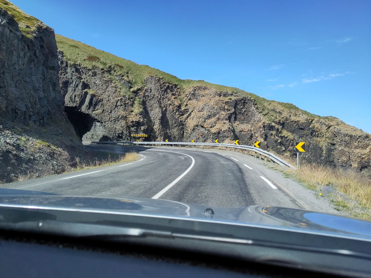 Straße biegt um eine dunkle Felswand, aus dem Auto fotografiert