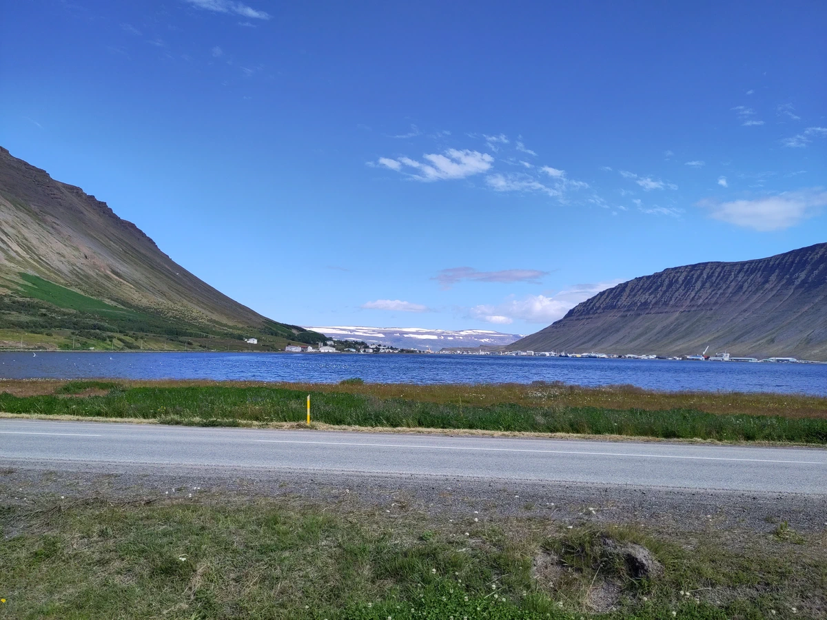 Fjord mit einem Ort am anderen Ufer zwischen steilen Berghängen