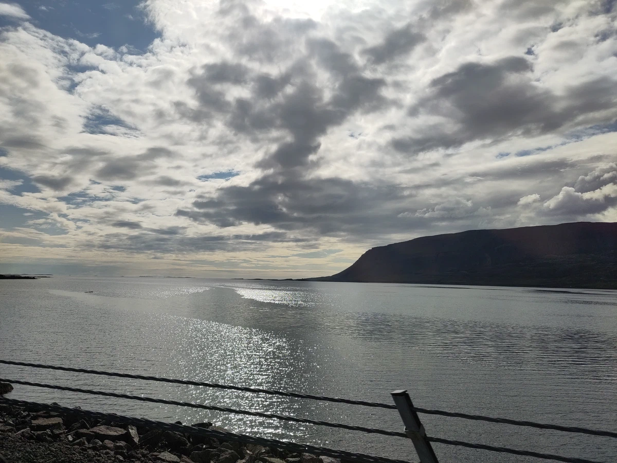 Fjord im Gegenlicht unter dunklen Wolken