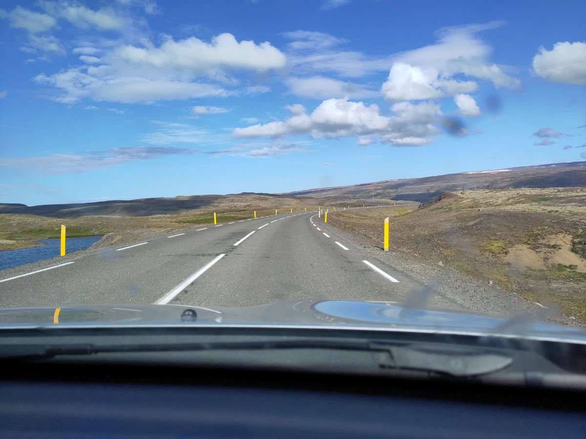 Straße über eine karge Hochebene mit gelben Leitpfosten, aus dem Auto fotografiert
