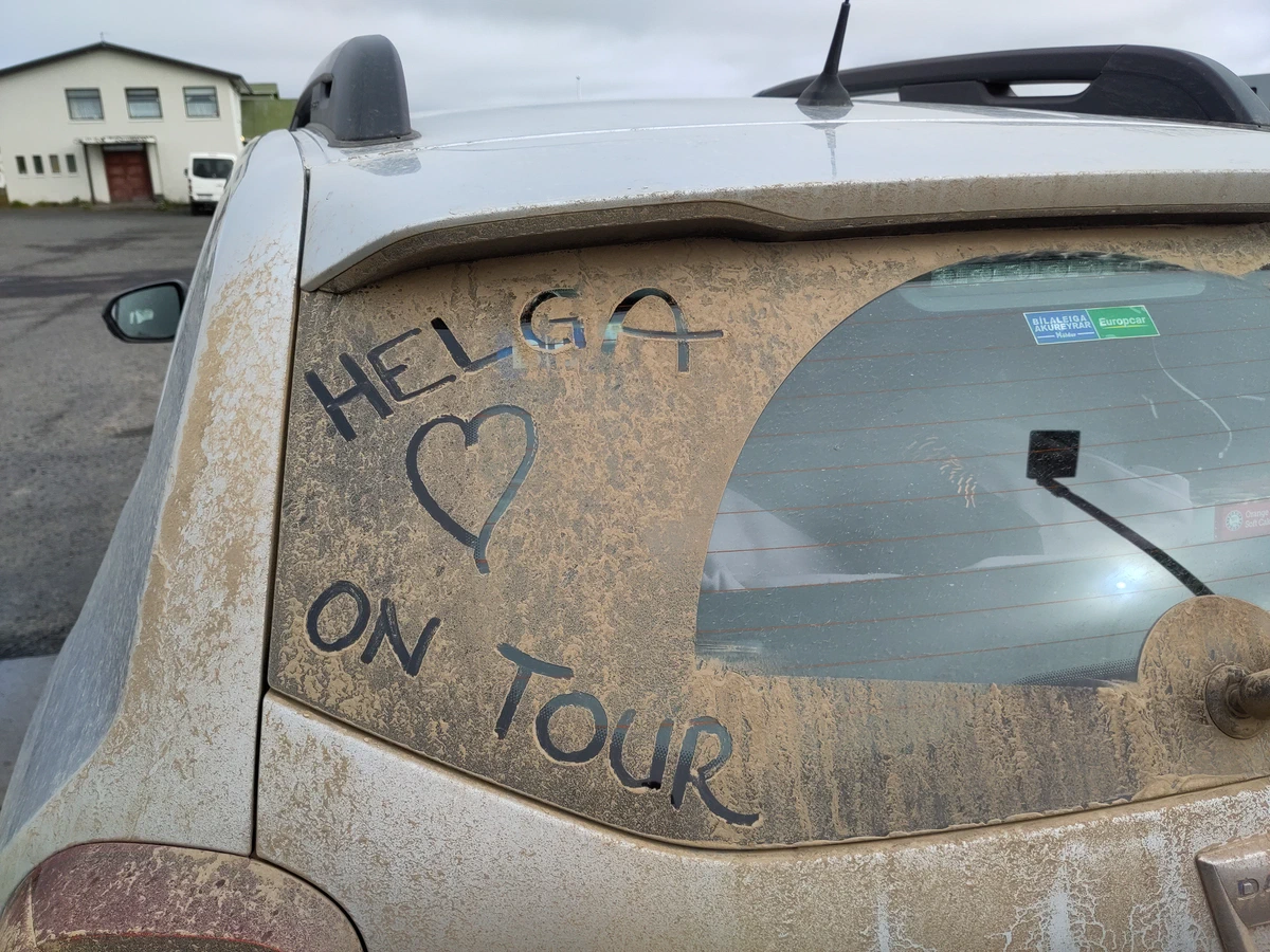 Staubiges Autoheck, in den Schmutz geschrieben: Helga on Tour mit einem Herz