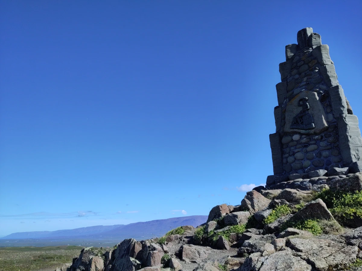 Denkmal aus aufgeschichteten Steinen auf einem Felshügel unter blauem Himmel