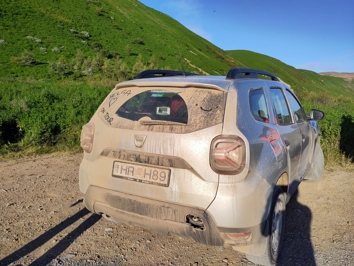 Das völlig verstaubte Auto auf einem Schotterweg in der Abendsonne