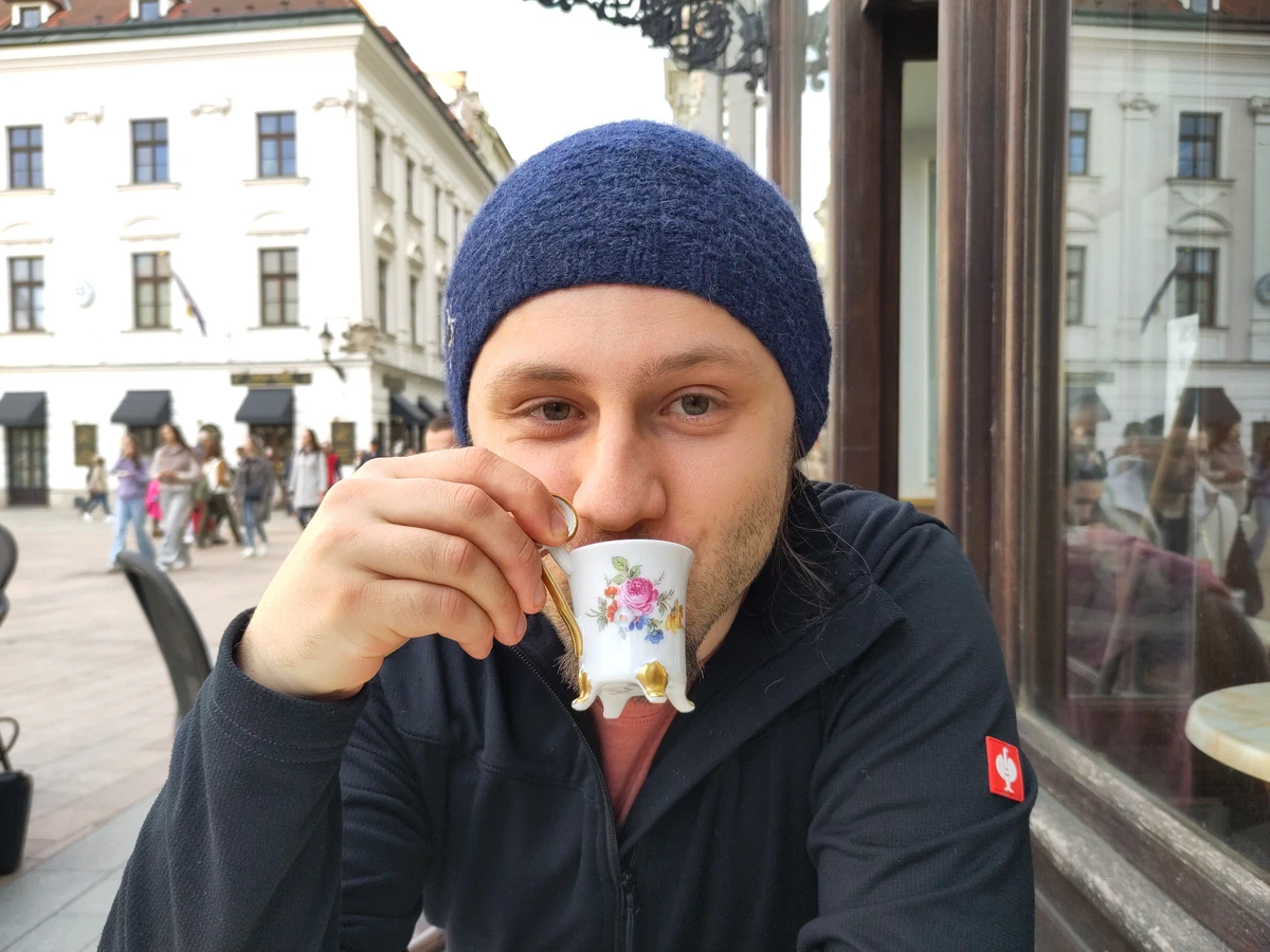 Ein Mann mit blauer Mütze trinkt Kaffee aus einer geblümten Porzellantasse
