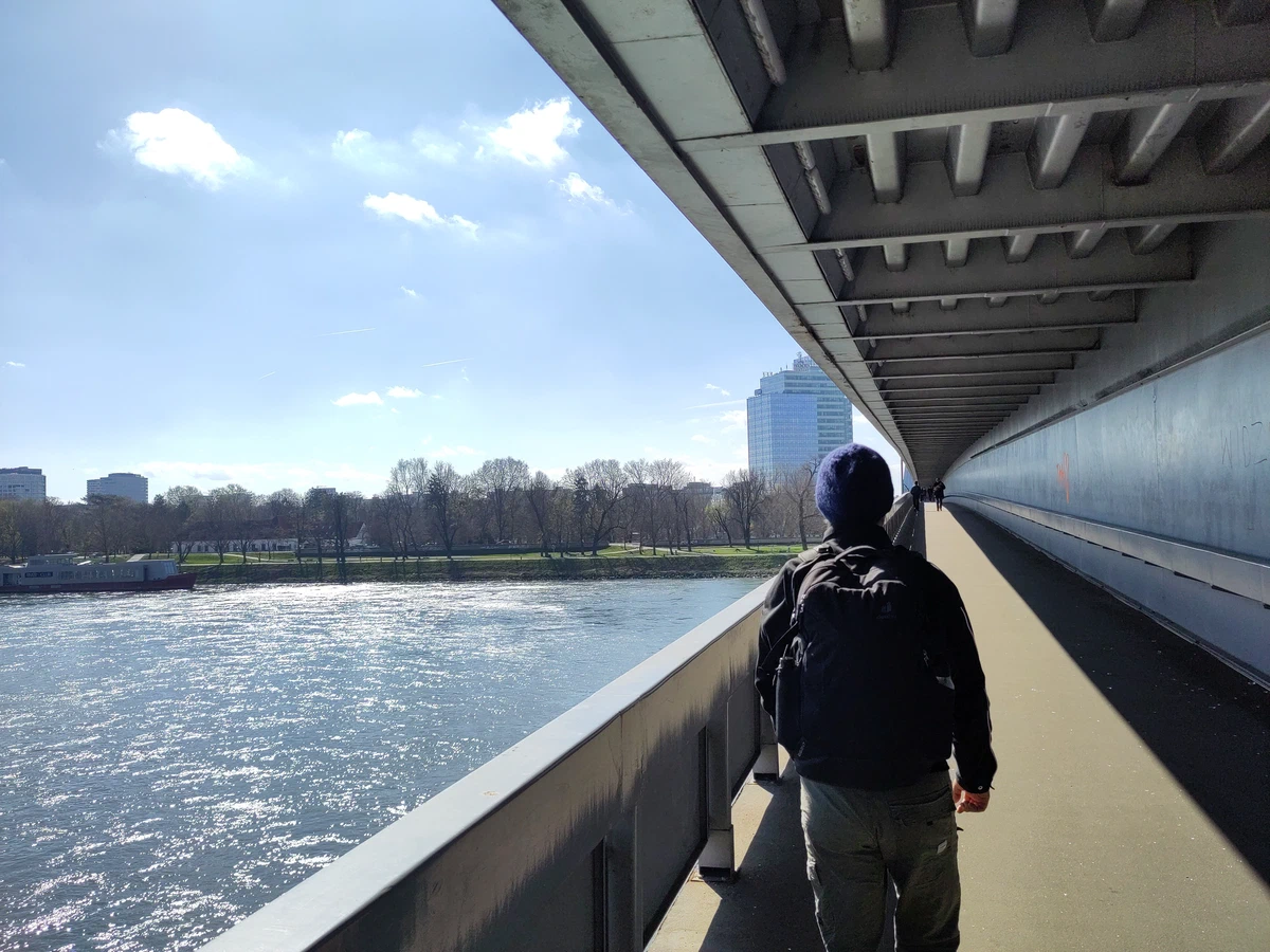 Eine Person geht auf der Fußgängerebene unter der Brücke über die Donau