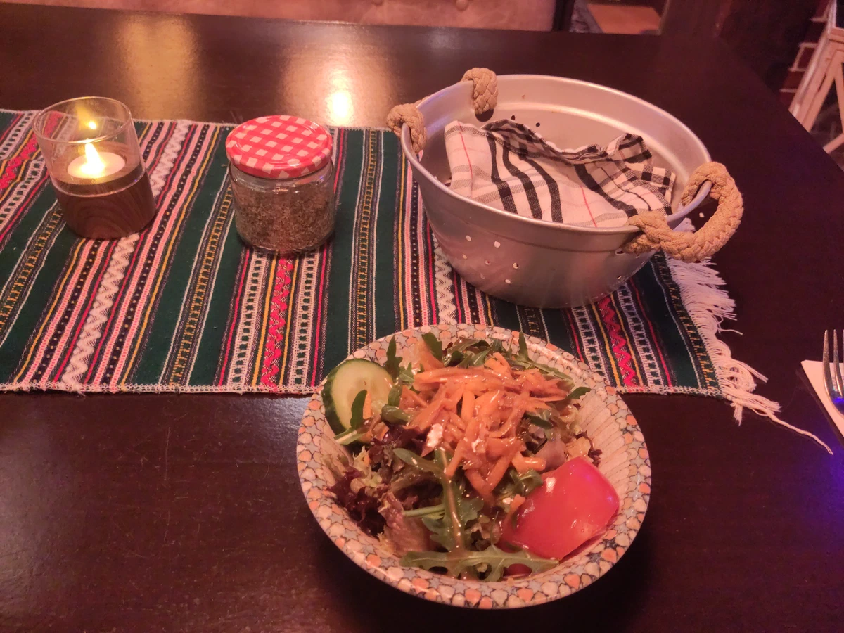 Gemischter Salat und ein Brotkorb auf einem gewebten Tischläufer