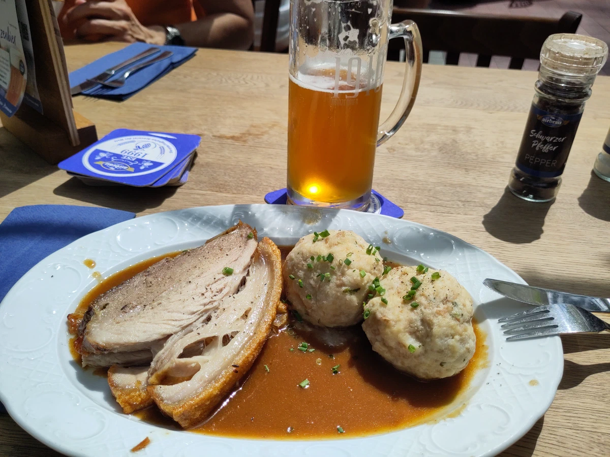 Schweinsbraten mit zwei Semmelknödeln und Bratensauce, dazu ein Bier