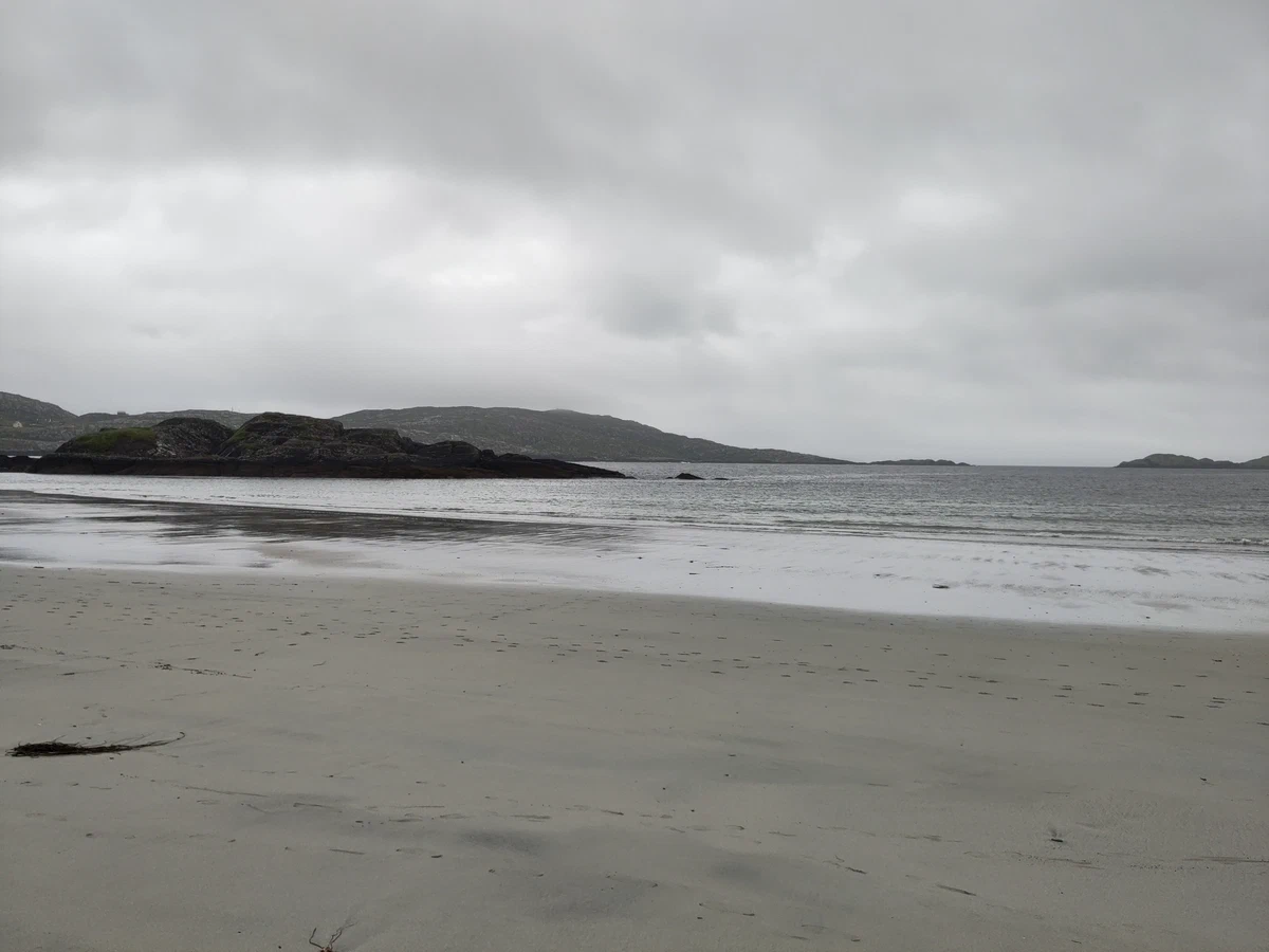 Leerer Sandstrand bei Ebbe mit Inseln im Hintergrund