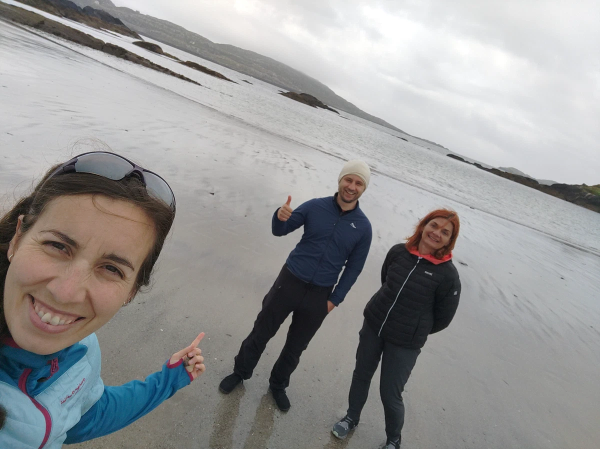 Selfie von oben: drei gut gelaunte Personen am Strand
