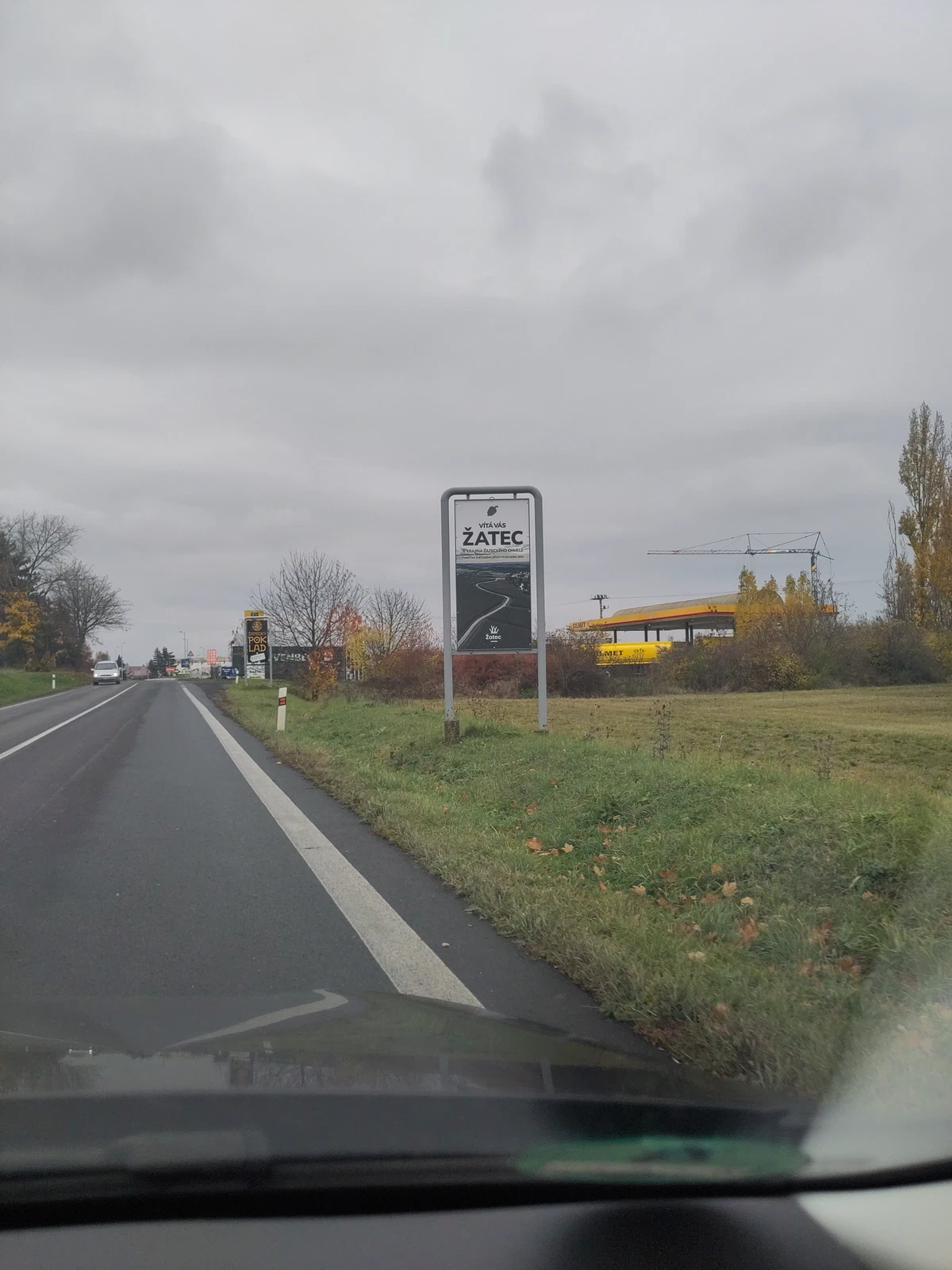 Ortsschild von Žatec an der Landstraße, aus dem Auto fotografiert
