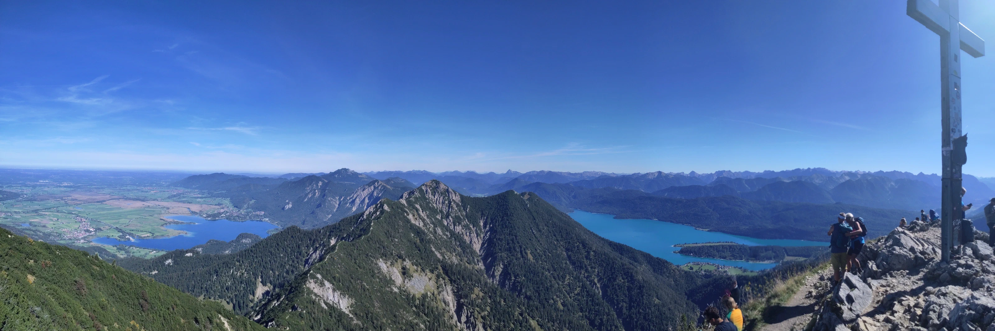 Panorama vom Heimgarten: links Kochelsee und Voralpenland, in der Mitte der Grat zum Herzogstand, rechts der Walchensee und das Gipfelkreuz