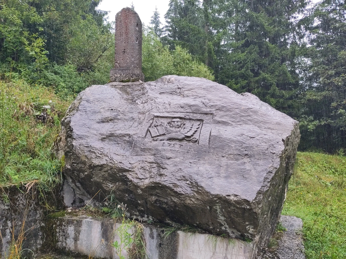 Verwitterter Grenzstein auf einem großen Felsblock mit eingemeißeltem Relief