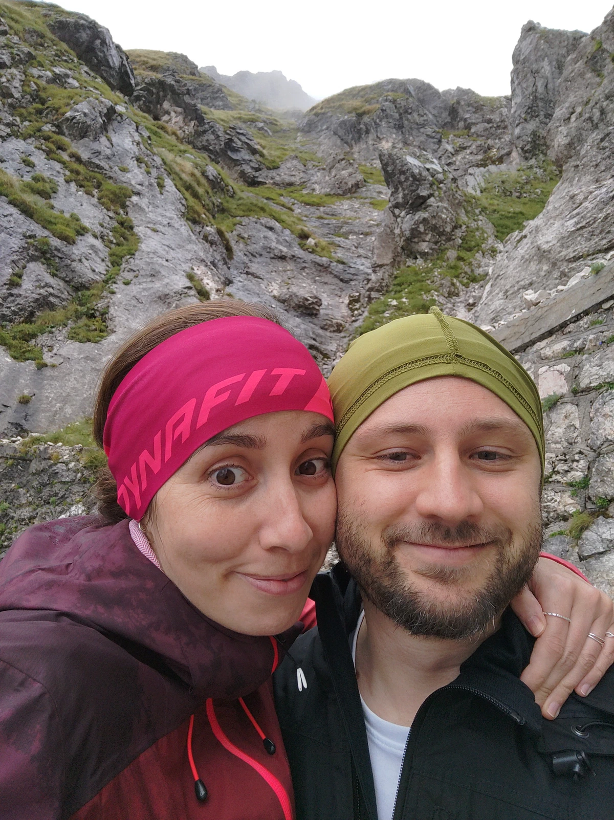 Selfie von uns beiden mit Stirnband und Mütze zwischen den Felswänden am Mangart