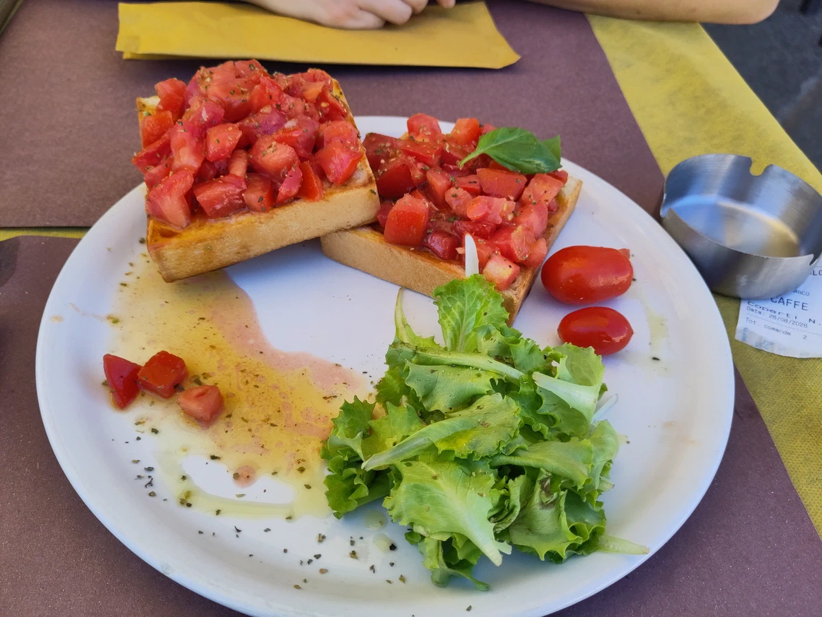 Bruschette mit Tomaten und ein kleiner Salat auf einem Teller