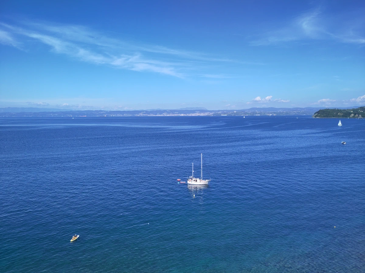 Tiefblaues Meer mit einem Segelboot vor der Küste von Piran