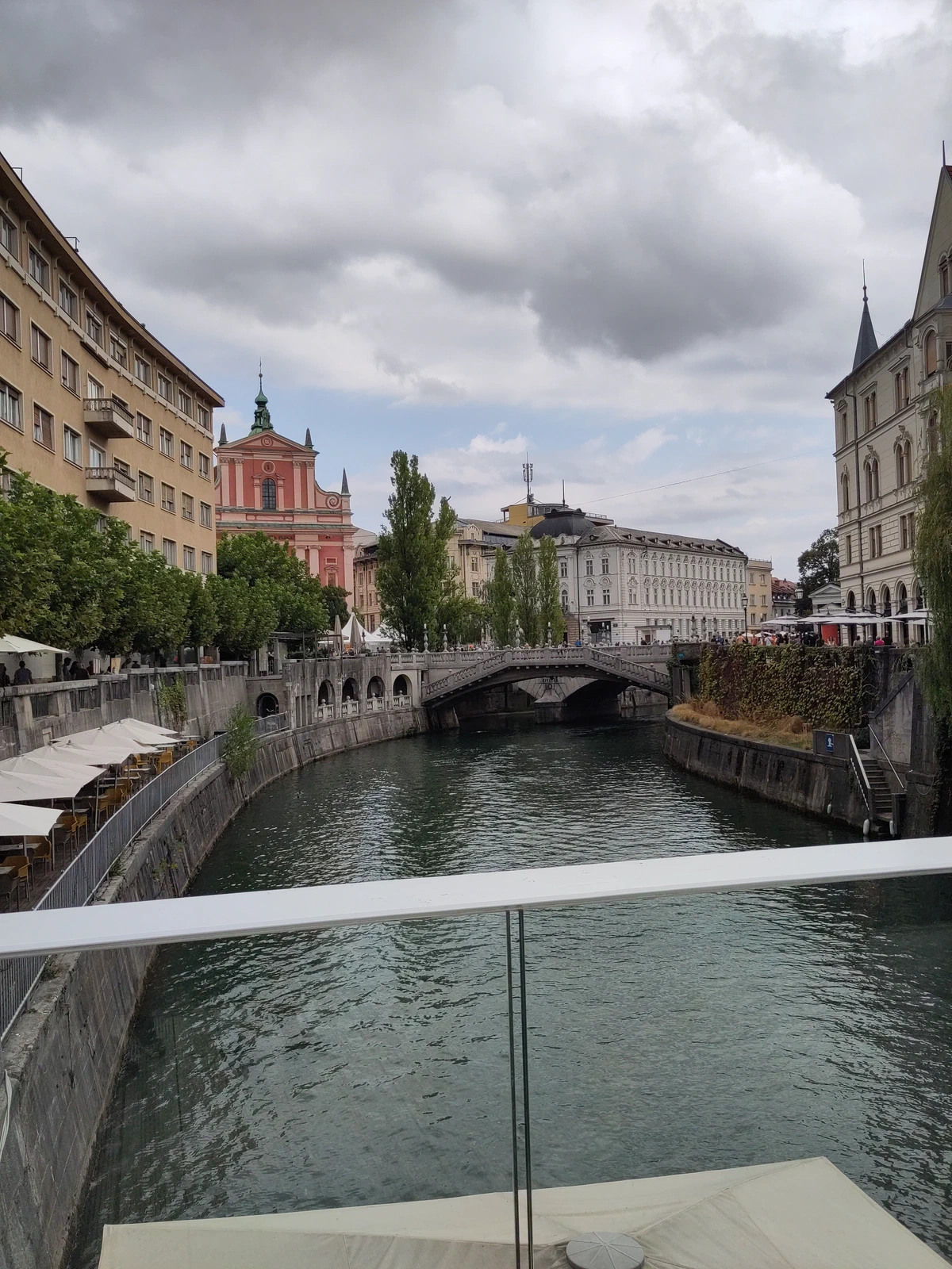 Die Ljubljanica in Ljubljana mit Brücke und der rosa Franziskanerkirche unter Wolken