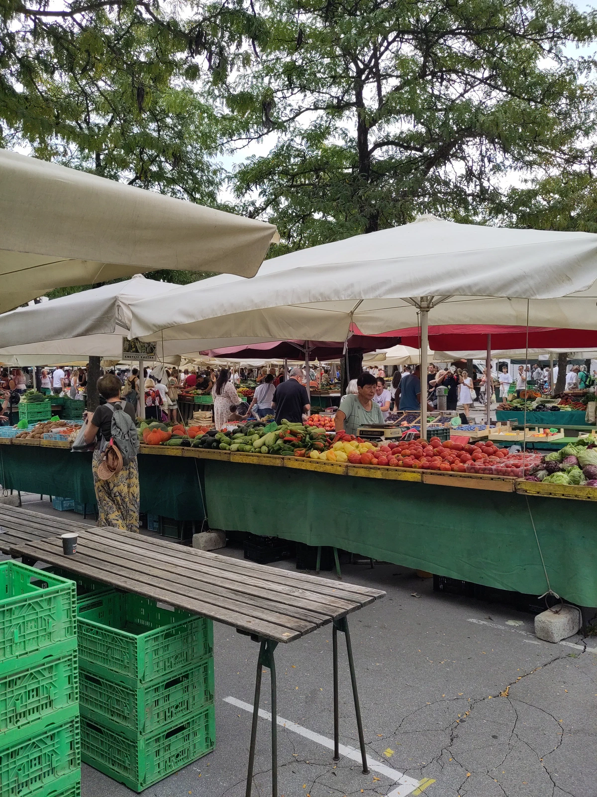 Marktstände mit Obst und Gemüse unter großen Schirmen