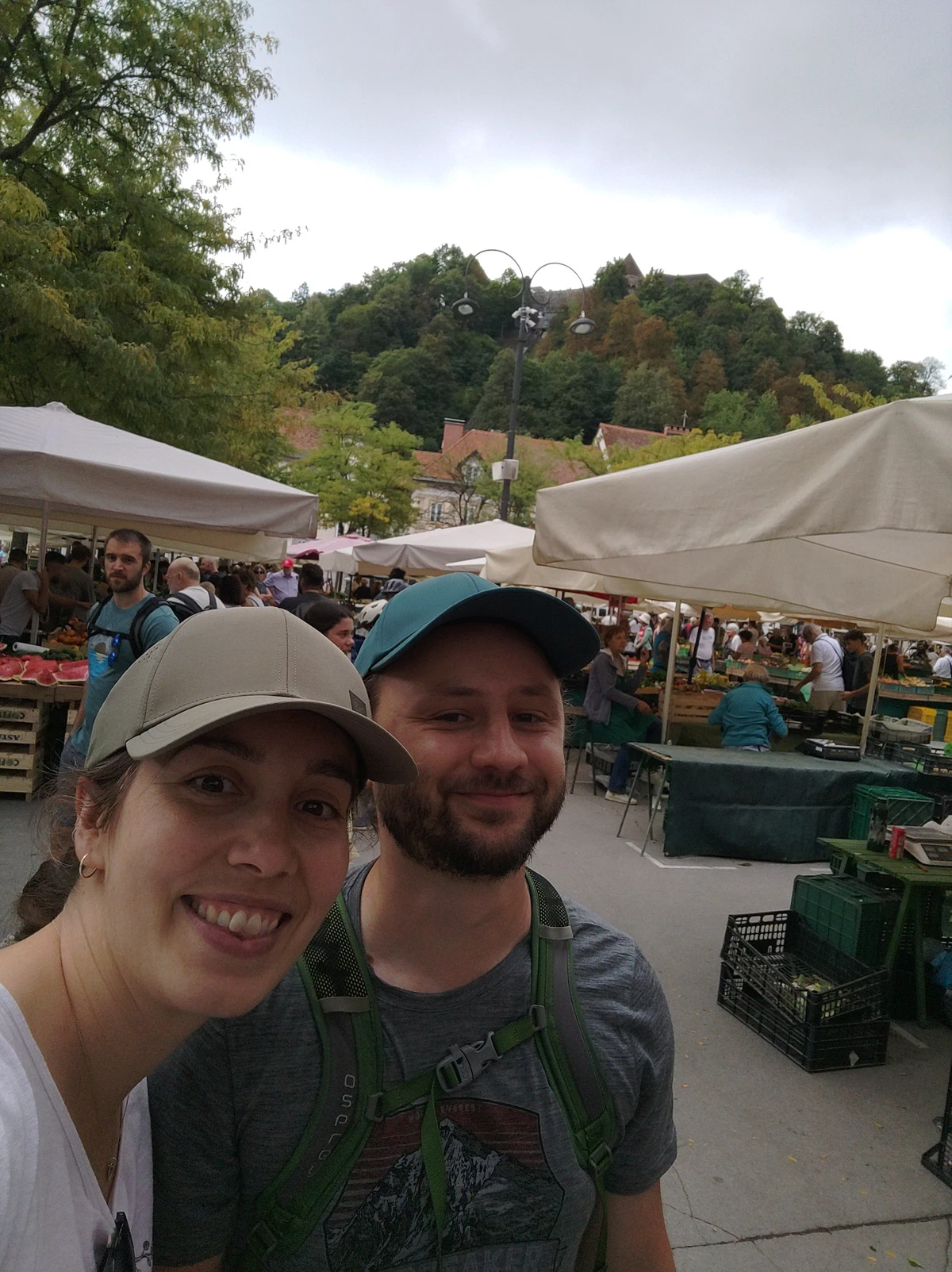 Selfie von uns beiden mit Kappen am Markt, dahinter der Burghügel