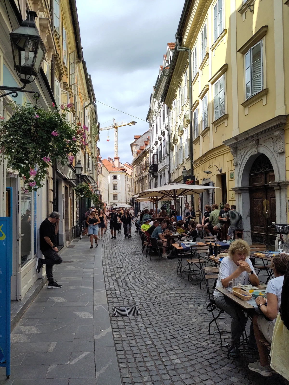 Gasse in der Altstadt von Ljubljana mit Straßencafés und gelben Fassaden